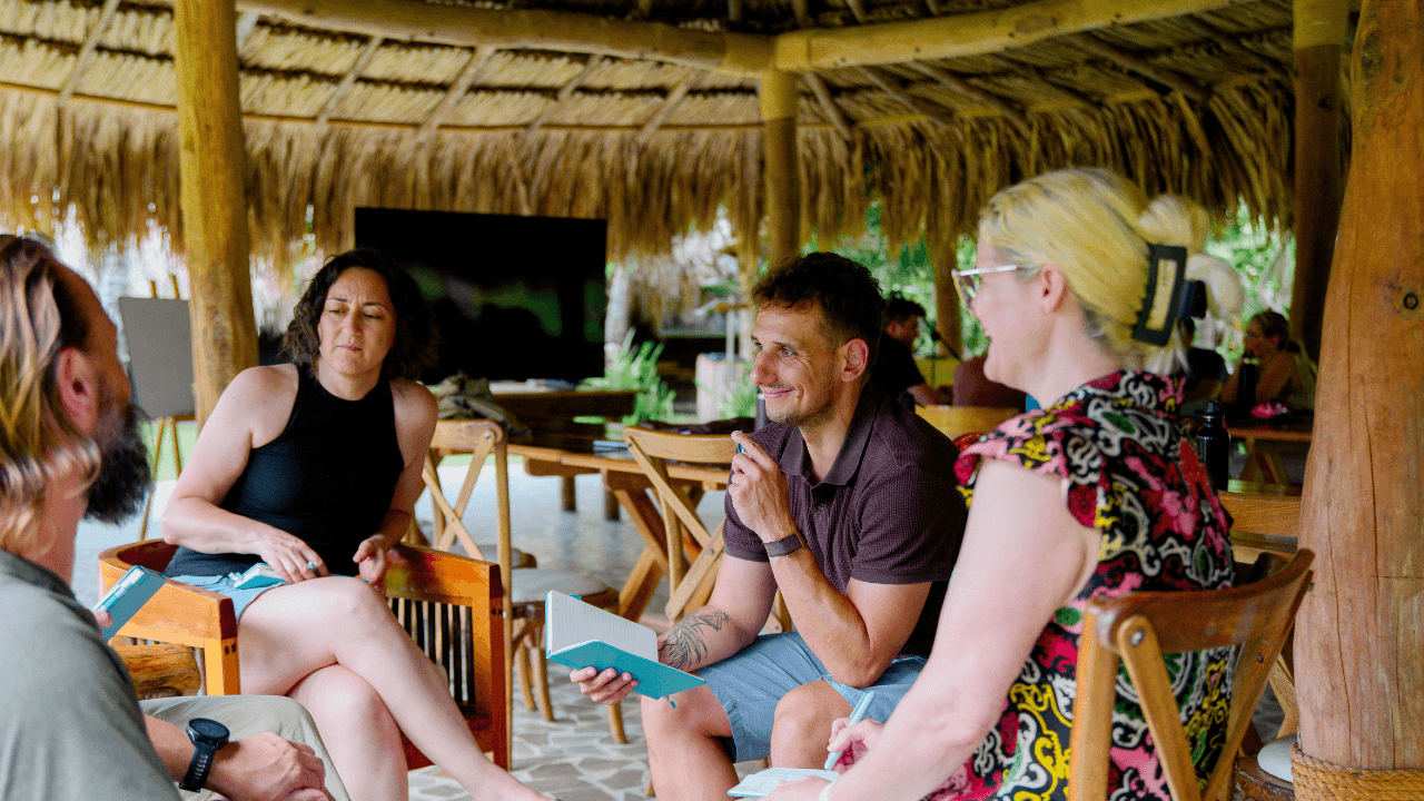 Filip Sardi with three founders in a circle of chairs under a thatched roof at the mastermind in Colombia, notebooks open